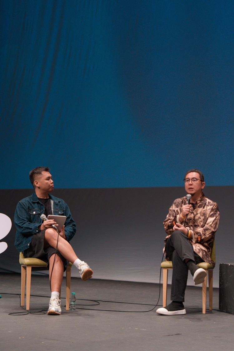 A person sitting in chairs with a microphone
AI-generated content may be incorrect.